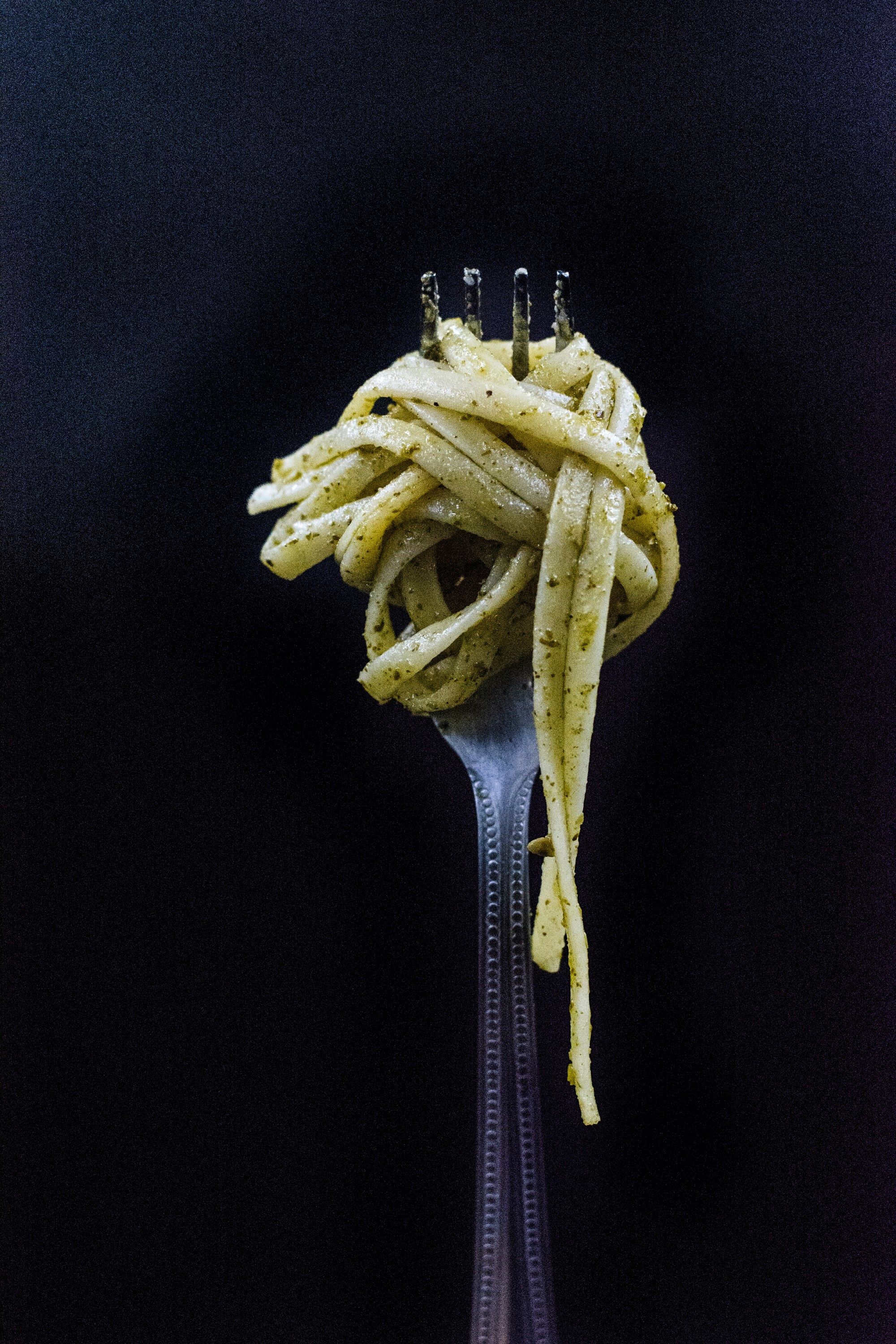 Spagheti with pesto sauce rolled on a fork